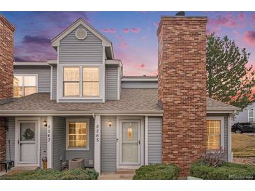 Charming townhome with a brick chimney and well-maintained landscaping at dusk at 8265 W 90Th Pl, Broomfield, CO 80021