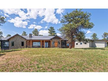 Charming home featuring a stone and wood exterior, a covered porch, and a well-manicured lawn at 25350 Ridge Way, Golden, CO 80401