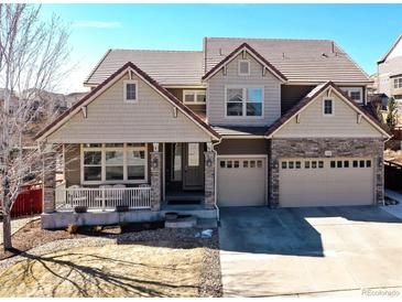 Charming two-story home featuring a welcoming front porch, three-car garage, and beautiful stone accents at 1665 Avery Way, Castle Rock, CO 80109