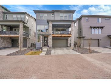Modern three-story home with a stone accent facade, balcony, and two-car garage at 15794 W Girard Ave, Morrison, CO 80465