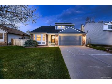 Charming home featuring a well-manicured lawn, gray siding, brick accents, and an attached two-car garage at 7054 S Flower Ct, Littleton, CO 80128