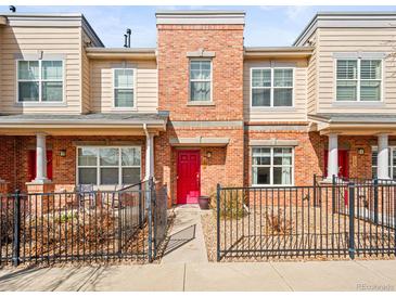 Charming townhome with brick facade, red door, and cozy front patio area at 7323 Lowell Blvd, Westminster, CO 80030