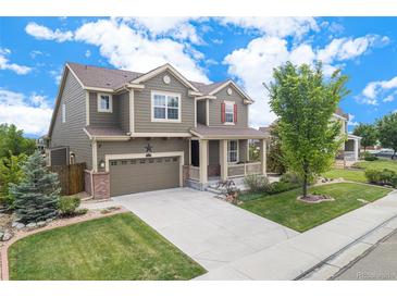 Charming two-story home featuring a well-manicured lawn, covered front porch, and attached two-car garage at 13326 Olive Way, Thornton, CO 80602