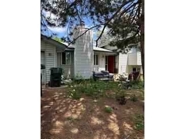 Overgrown front yard featuring a white house with a red door and discarded furniture at 3150 W 134Th Ave, Broomfield, CO 80020