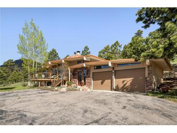 Charming home featuring a two-car garage, a stone facade, and a large wooden deck at 107 Elk Dr, Evergreen, CO 80439