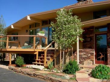 Charming home featuring a stone facade, inviting deck, and beautiful landscaping at 107 Elk Dr, Evergreen, CO 80439