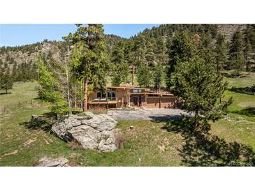 Mid-century modern home with mature trees sits on a large lot overlooking a valley and surrounding mountains at 107 Elk Dr, Evergreen, CO 80439