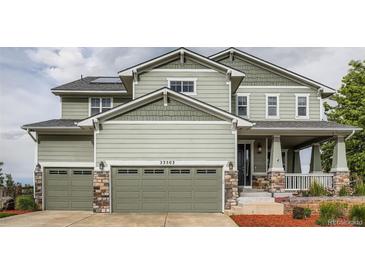 Charming two-story home featuring a two-car garage, covered porch with stone accents and manicured front lawn at 23503 E Minnow Dr, Aurora, CO 80016