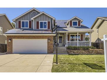 Charming two-story home featuring a brick facade, gray siding, solar panels and a welcoming front porch at 13212 Clermont Cir, Thornton, CO 80241