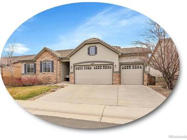 Charming home featuring a three-car garage, stone accents, and neutral stucco exterior at 10770 Hillrose St, Parker, CO 80134
