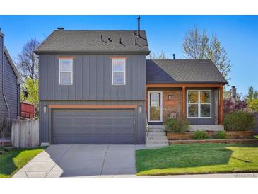 Charming two-story home featuring a well-manicured lawn, a two-car garage, and a cozy brick porch area at 11446 W 105Th Dr, Broomfield, CO 80021
