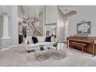 Bright living room with a modern sofa, round tables, piano, and an open staircase to the second floor at 16361 Parkside Dr, Parker, CO 80134