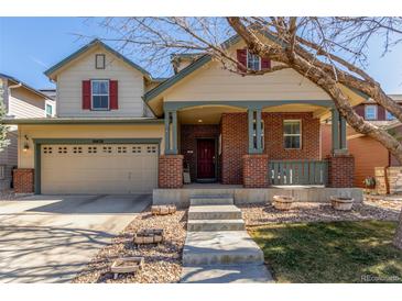 Charming two-story home with brick accents, covered porch, and a well-manicured front yard on a sunny day at 10438 Olathe Way, Commerce City, CO 80022
