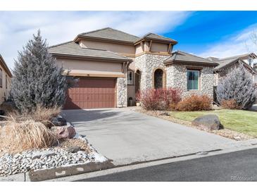 Attractive home featuring a stone facade, a large driveway, a tile roof, and manicured landscaping at 16 Willowcroft Dr, Littleton, CO 80123