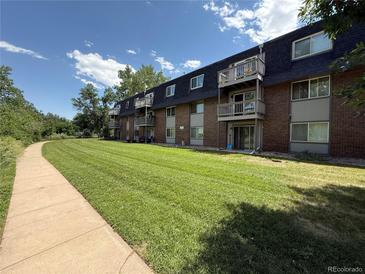 Well-maintained brick apartment building with balconies overlooking manicured lawn and a walking path at 309 E Highline Cir # 102, Centennial, CO 80122