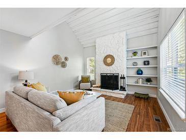 Bright living room with a stone fireplace, built-in shelves, and wood floors at 2645 S Xanadu Way # C, Aurora, CO 80014