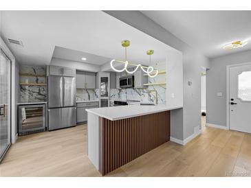 Modern kitchen with gray cabinets, stainless steel appliances, and a unique backsplash at 13254 E Asbury Dr, Aurora, CO 80014