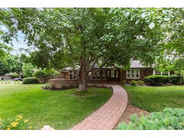 Well-manicured front yard featuring mature tree, lush lawn, and brick walkway leading to a welcoming home at 4 Doral Ln, Littleton, CO 80123