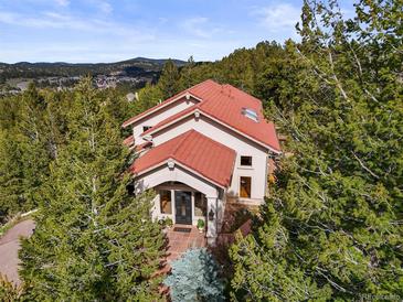 Stunning home with red tile roof nestled in the trees, offering scenic views at 1425 Autumnwood Ln, Evergreen, CO 80439