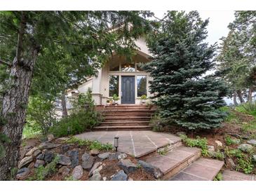 Inviting front entrance with stone walkway and mature trees providing shade and curb appeal at 1425 Autumnwood Ln, Evergreen, CO 80439