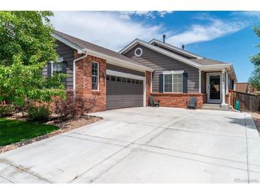 Charming home featuring gray siding, a brick facade, an attached two-car garage, and a well-maintained front yard at 2209 Lupine Pl, Erie, CO 80516