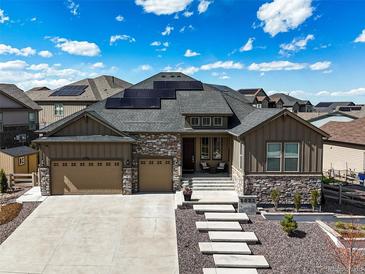 Charming home with a stone-accented facade, three-car garage, concrete driveway and solar panels at 8023 Gore Creek Ln, Littleton, CO 80125