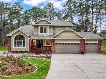 Charming two-story home with brick accents, an inviting front porch, a three-car garage, and landscaped front yard at 10 Long Bow Cir, Monument, CO 80132