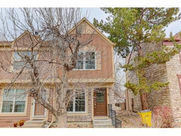 Charming two-story townhome with a stone and siding exterior, complemented by mature trees at 11973 E Kepner Dr, Aurora, CO 80012