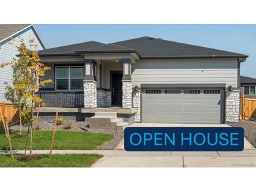 Ranch-style home with gray siding, stone accents, and a two-car garage at 17305 E 91St Pl, Commerce City, CO 80022