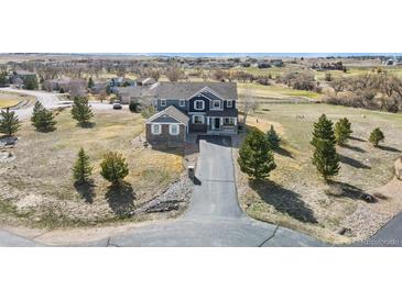 Two-story house with grey siding, stone accents, long driveway and well-maintained landscaping at 5285 La Quinta Cir, Elizabeth, CO 80107