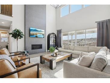Bright living room with fireplace, large windows, and comfortable seating arrangement at 6361 Kenzie Cir, Castle Pines, CO 80108