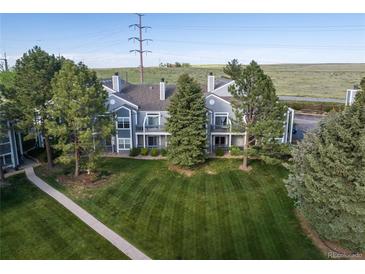 Well maintained gray townhome featuring a lush lawn and mature trees at 7452 Singing Hills Dr, Boulder, CO 80301