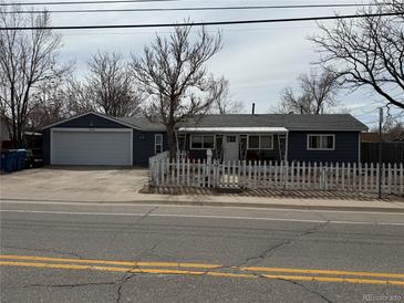 Charming single-story home with a white picket fence and a spacious two-car garage at 7060 E 60Th Ave, Commerce City, CO 80022
