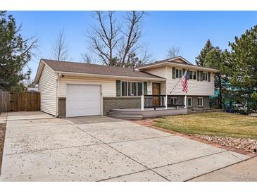 Charming home with an attached garage, a well-maintained lawn, and a cozy front porch at 11950 E Exposition Ave, Aurora, CO 80012