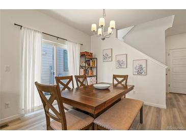 Bright dining room boasts modern light fixture, seating for six, and sliding glass doors for ample natural light at 23920 E 34Th Ave, Aurora, CO 80019