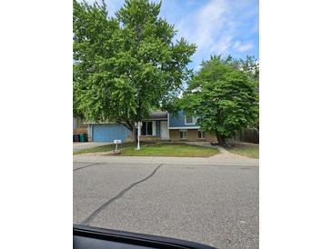 Charming single-Gathering home with blue siding, mature trees, and a well-maintained front yard at 321 S 26Th Ave, Brighton, CO 80601