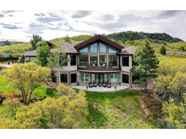 Stunning two-story home featuring a wall of windows, stone accents, and a spacious patio with outdoor seating at 580 Summer Mist Cir, Castle Rock, CO 80104