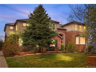 Inviting two-story brick home featuring a lush front lawn and mature landscaping at 286 Claymoor Ct, Castle Pines, CO 80108