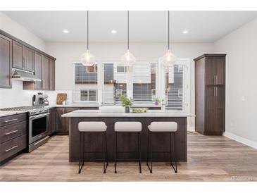 Modern kitchen features a center island with barstool seating, sleek cabinets, and stainless steel appliances at 5165 Vivian St, Wheat Ridge, CO 80033