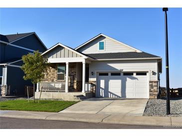 Charming home featuring a stone-accented porch and a two-car garage, all under a clear blue sky at 45871 Orchid Ave, Bennett, CO 80102