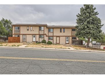 A charming two-story townhome features a neutral exterior, a small porch, and a well-maintained front yard at 8770 Rainbow Ave # B4, Denver, CO 80229