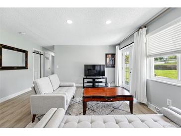 Bright living room features light gray walls, wood flooring, and access to the backyard at 9175 Cole Dr, Arvada, CO 80004