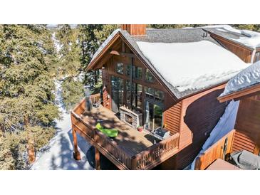Stunning exterior showcasing an expansive deck with a stone fireplace perfect for outdoor gatherings at 960 Whispering Pines Ln, Breckenridge, CO 80424
