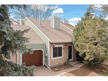 Charming home featuring stone accents, a brown garage door, and manicured landscaping at 19411 E Milan Cir, Aurora, CO 80013