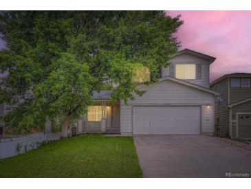 Charming two-story home with a well-manicured lawn and mature tree providing shade at sunset at 21767 Silver Meadow Ln, Parker, CO 80138