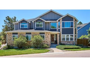 Two-story home showcasing a brick and navy blue exterior with a well-manicured lawn and mature shrubs at 7804 Silverweed Way, Lone Tree, CO 80124