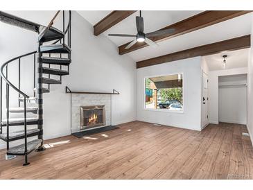 Bright living room features vaulted ceilings, exposed beams, a cozy fireplace, and a unique spiral staircase at 11820 Lincoln St, Northglenn, CO 80233