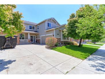 Two-story home featuring a manicured lawn, covered porch, and an attached two-car garage at 9994 Quintero St, Commerce City, CO 80022