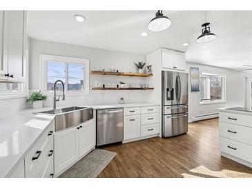 Bright kitchen features stainless steel appliances, farmhouse sink, open shelving, and gleaming hardwood floors at 767 Ellis St, Golden, CO 80401