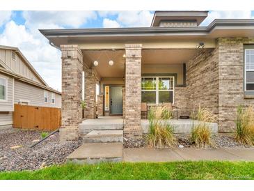 Inviting covered front porch with brick pillars and neutral paint scheme enhance the home's curb appeal at 9816 Kalispell St, Commerce City, CO 80022